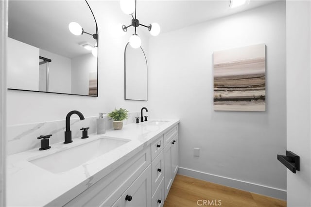 bathroom with a sink, baseboards, wood finished floors, and double vanity