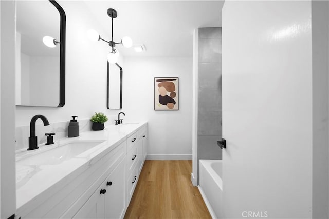 full bathroom with double vanity, wood finished floors, baseboards, and a sink