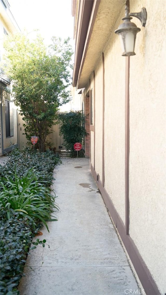 view of side of home with stucco siding, a patio, and fence