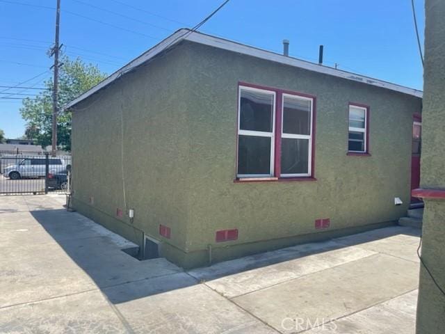 view of side of home with concrete driveway, fence, and stucco siding