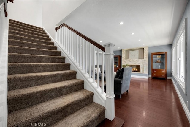 stairway with baseboards, recessed lighting, a fireplace, ornate columns, and wood-type flooring