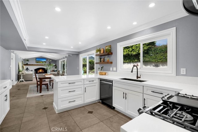 kitchen featuring a peninsula, ornamental molding, a lit fireplace, a sink, and dishwasher