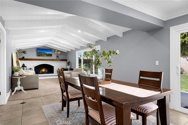 dining space featuring lofted ceiling with beams, crown molding, light tile patterned flooring, and a fireplace