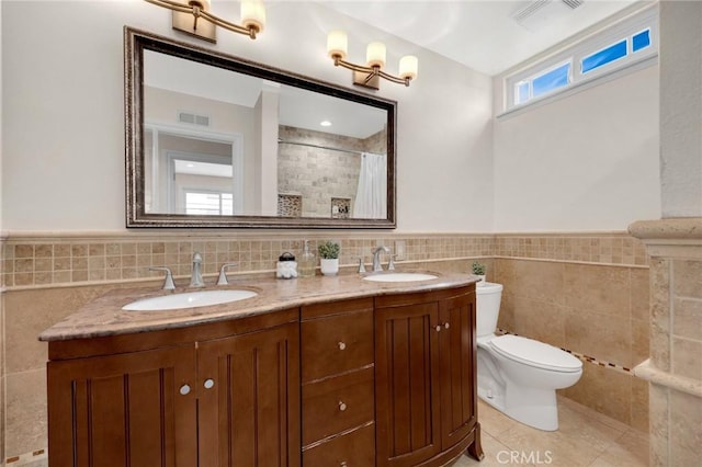 full bath with tile walls, toilet, visible vents, and a sink