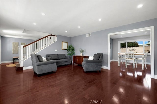 living area with visible vents, baseboards, dark wood-style flooring, and stairway