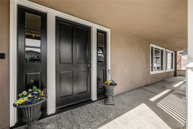 doorway to property with stucco siding and a porch