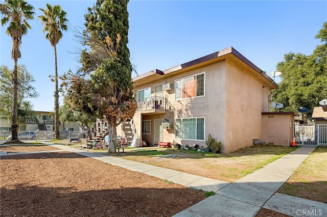 view of property featuring a gate, stucco siding, a front yard, and fence