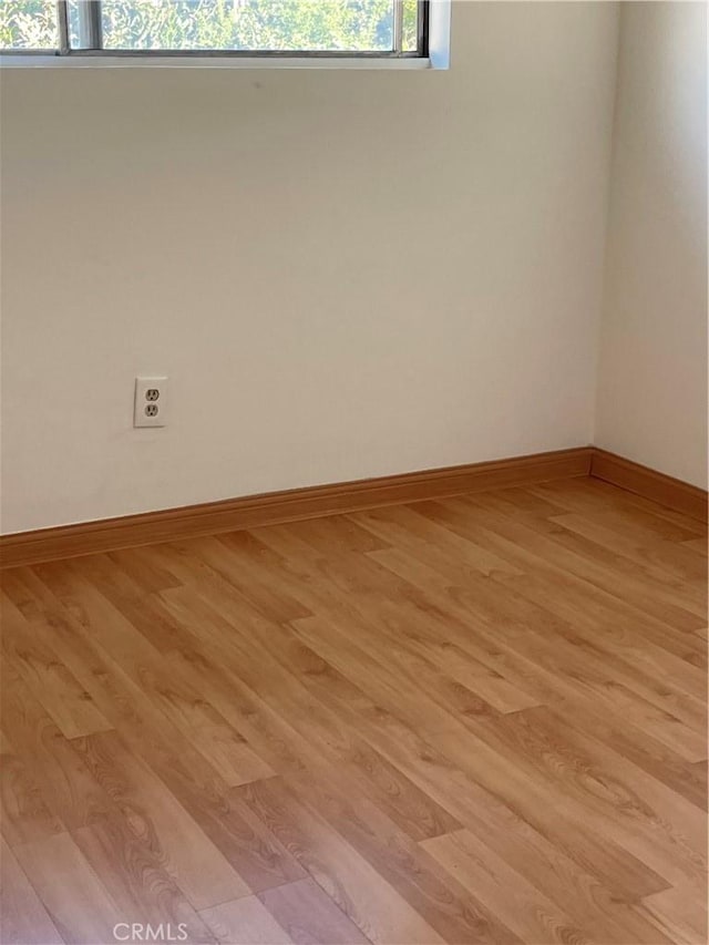 spare room featuring light wood-style flooring and baseboards