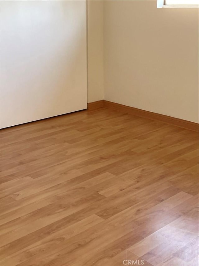 spare room featuring light wood-style flooring and baseboards