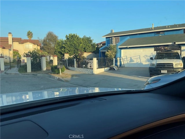 view of front of home with concrete driveway, an attached garage, and fence