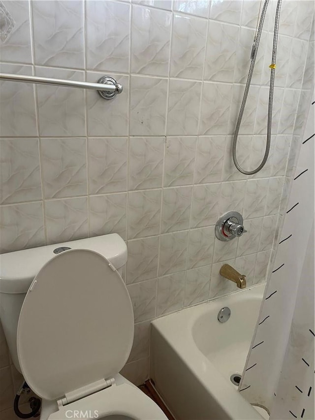 bathroom featuring tile walls, toilet, and shower / bathtub combination with curtain