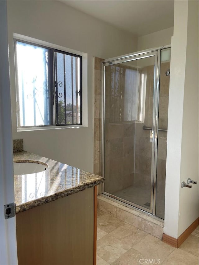 bathroom with vanity, tile patterned floors, baseboards, and a stall shower