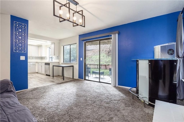 unfurnished living room with baseboards, light carpet, and a notable chandelier