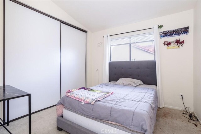 carpeted bedroom featuring lofted ceiling, baseboards, and a closet