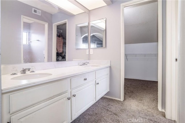 full bathroom featuring a sink, visible vents, a walk in closet, and double vanity