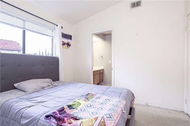 bedroom with visible vents, light carpet, lofted ceiling, connected bathroom, and baseboards