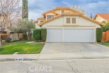 view of front facade with stucco siding, a front lawn, driveway, fence, and a garage