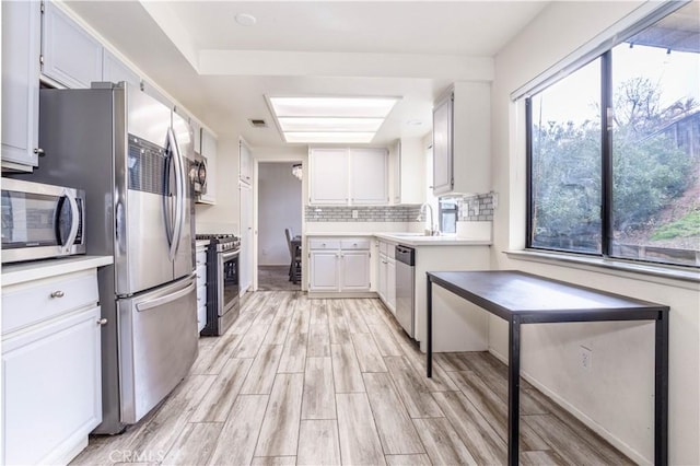 kitchen with light countertops, wood tiled floor, backsplash, and stainless steel appliances