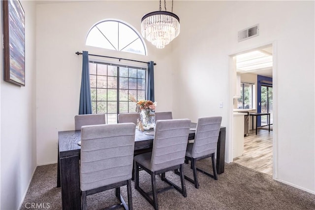 carpeted dining space with an inviting chandelier and visible vents