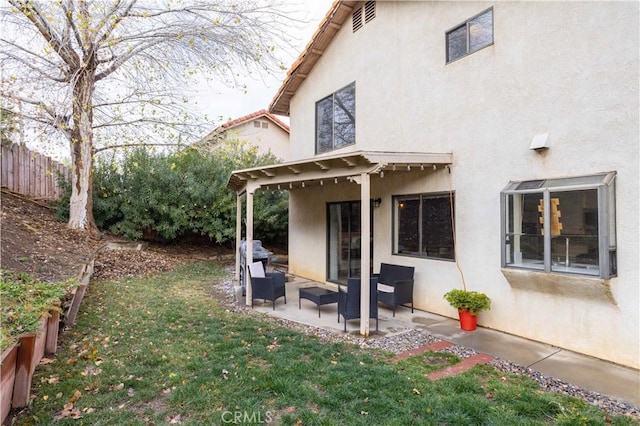 rear view of house featuring fence, stucco siding, an outdoor hangout area, a lawn, and a patio area