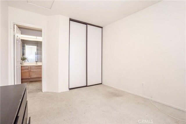 unfurnished bedroom featuring light colored carpet, a closet, and baseboards