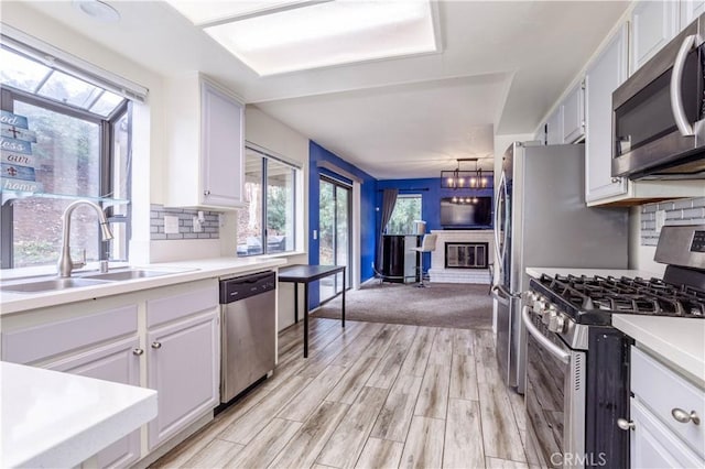 kitchen featuring a sink, light countertops, white cabinets, appliances with stainless steel finishes, and tasteful backsplash