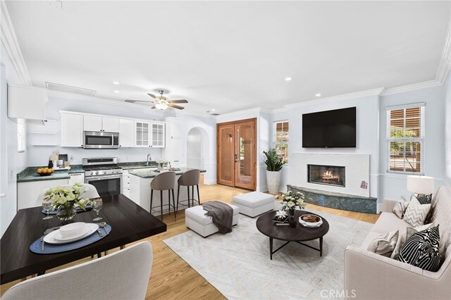 805 E Chase Dr, Corona, CA 92881 - living room with arched walkways, light wood finished floors, a glass covered fireplace, ornamental molding, and recessed lighting