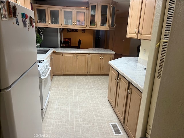 kitchen featuring white appliances, glass insert cabinets, visible vents, and a peninsula