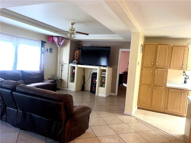 living area featuring a raised ceiling, light tile patterned floors, baseboards, and ceiling fan