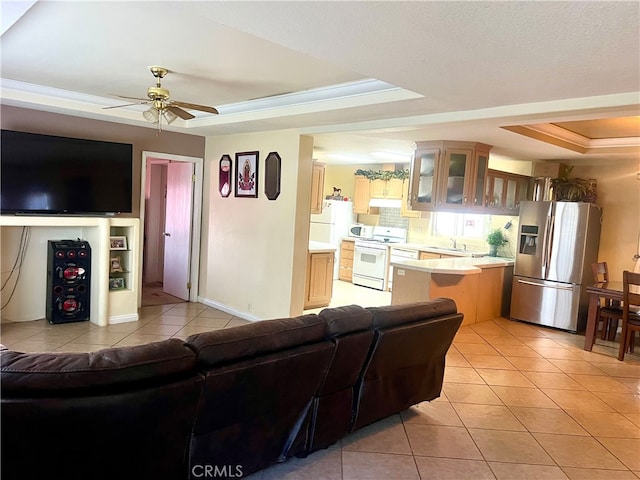 living room with light tile patterned floors, a ceiling fan, baseboards, crown molding, and a raised ceiling