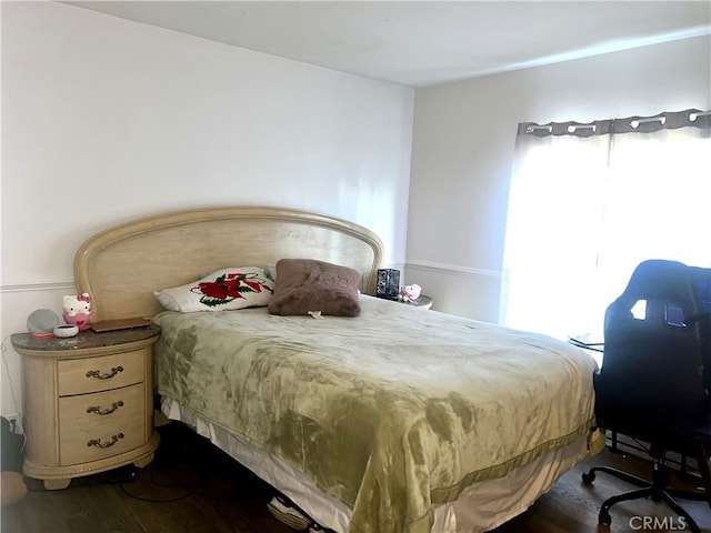 bedroom with multiple windows and dark wood-style flooring