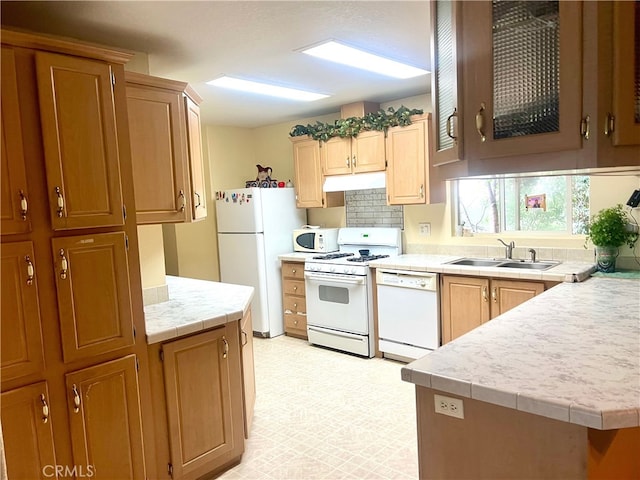 kitchen with a sink, under cabinet range hood, tasteful backsplash, white appliances, and light floors