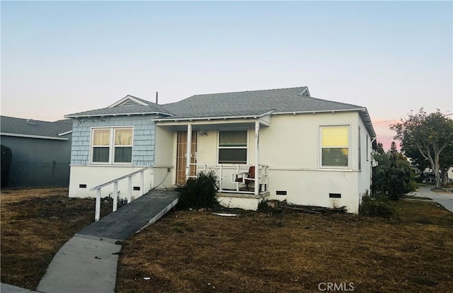 view of front of house featuring stucco siding, covered porch, roof with shingles, and crawl space