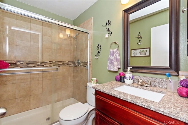 bathroom with vanity, a shower stall, and toilet