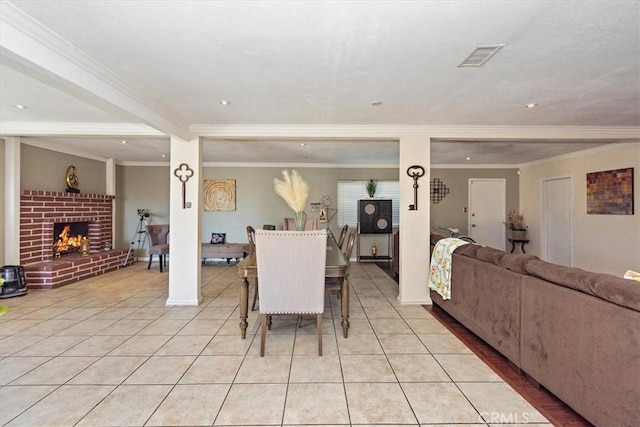 dining area featuring visible vents, a brick fireplace, light tile patterned flooring, and ornamental molding