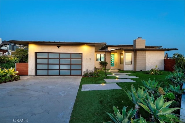 view of front of property with stucco siding, a chimney, concrete driveway, and an attached garage