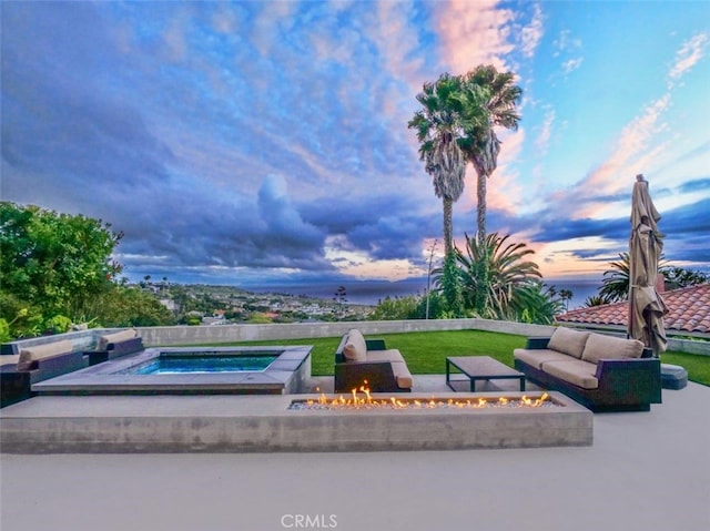 patio terrace at dusk featuring a fire pit and an in ground hot tub