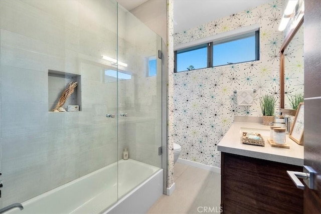 bathroom with vanity, baseboards, wallpapered walls, toilet, and combined bath / shower with glass door