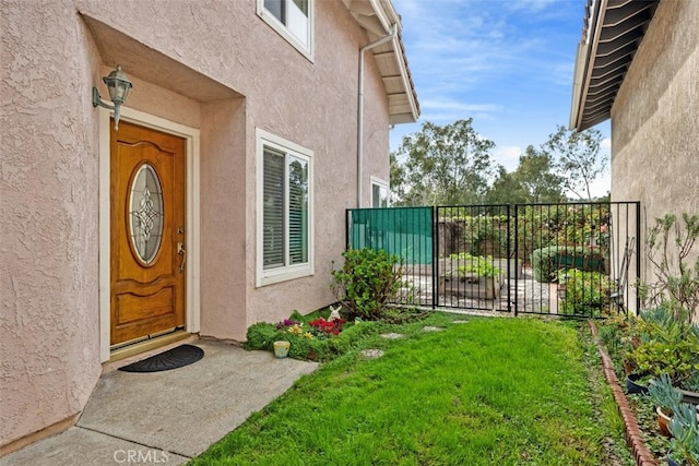 property entrance featuring stucco siding, a lawn, and fence