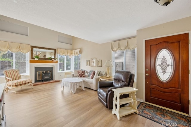 foyer entrance with light wood-style floors, baseboards, and a textured ceiling