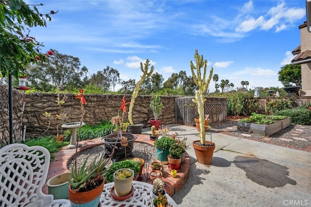 view of patio with a vegetable garden, a fire pit, and a fenced backyard