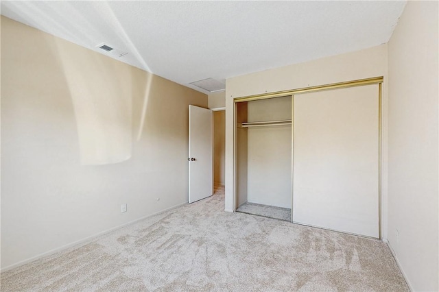 unfurnished bedroom with light carpet, visible vents, and a closet