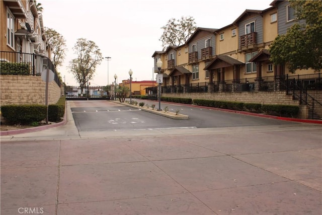 view of road with a gated entry, a residential view, curbs, and traffic signs