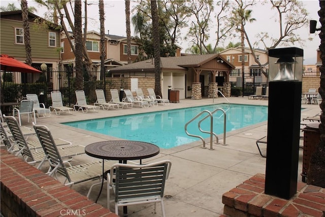 community pool featuring a patio, fence, and a residential view