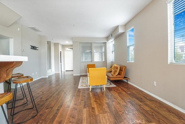 living area with visible vents, baseboards, and wood finished floors