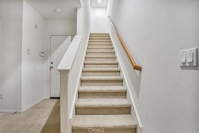 stairs featuring baseboards and carpet