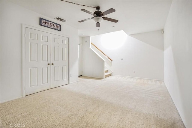 unfurnished living room with stairs, a ceiling fan, visible vents, and carpet floors