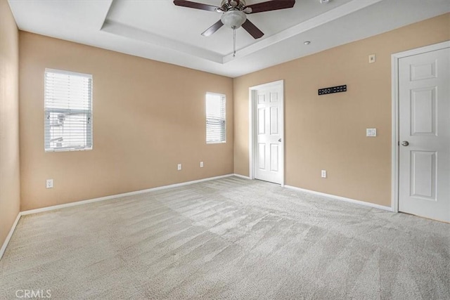 interior space featuring a tray ceiling, multiple windows, baseboards, and carpet flooring