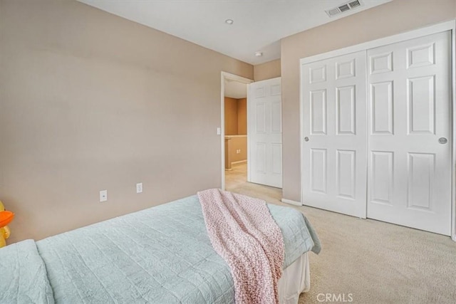 bedroom featuring light colored carpet, visible vents, and a closet