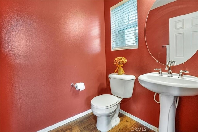 bathroom with a sink, baseboards, toilet, and wood finished floors